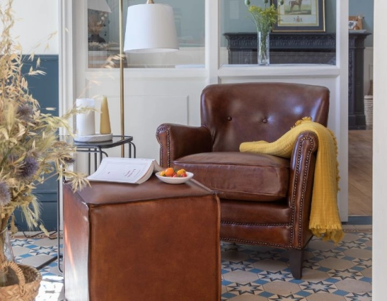 Fauteuil club cuir marron soutenu accoudoirs cloutés