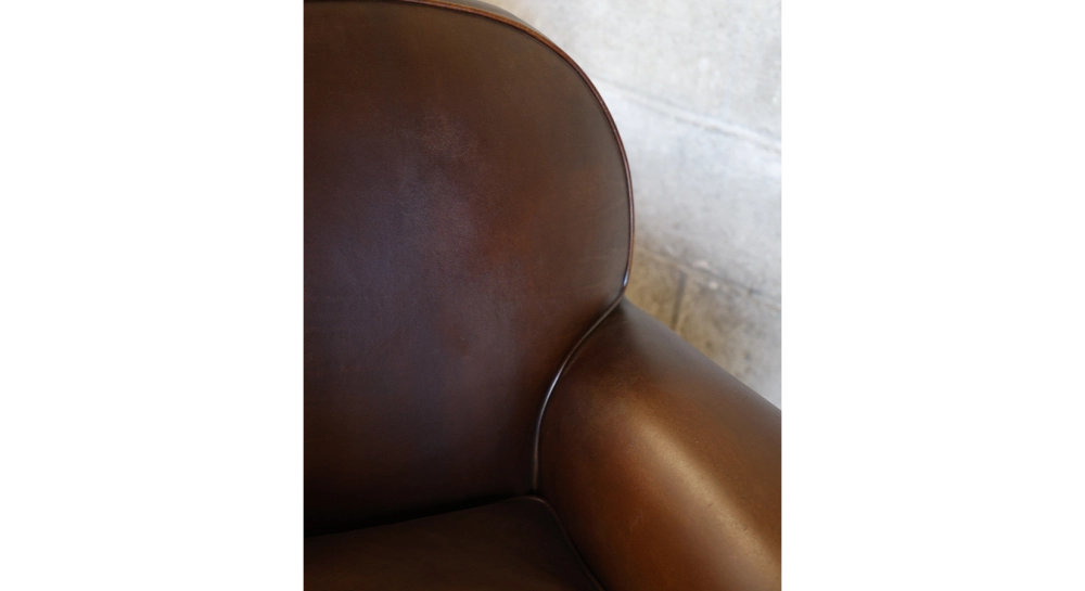 Fauteuil club cuir marron soutenu accoudoirs passepoil